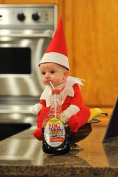 a baby elf sitting on top of a counter with a bottle in it's mouth