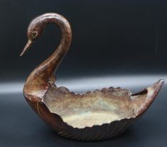 a ceramic bowl with a bird on it's body in front of a black background