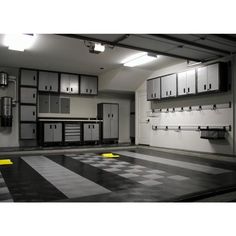 an empty garage with black and white checkerboard flooring, cabinets and lights