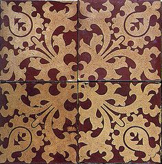 an intricately designed tile with red and gold designs on the bottom, in two different colors