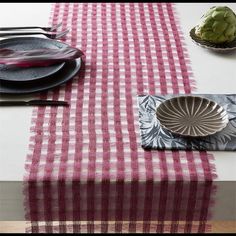 the table is set with black and white plates, silverware, and pink napkins