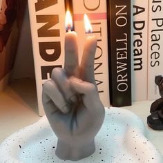 a candle that is in the shape of a hand on top of a white plate