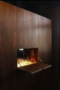 a shelf with some glasses on it in a room that has wood paneled walls