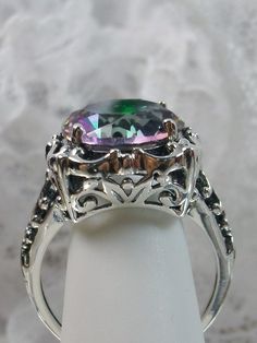 6 carat Simulated or Natural Rainbow Mystic Topaz Solid Sterling Silver RingSpeechless Design#D103 This filigree ring is a reproduction of a sterling silver Victorian antique with a stunning 6 carat Mystic Topaz gemstone solitaire. Please choose between simulated or natural gemstones. This full cut round faceted gem is 12mm in diameter. The inside of the band is marked 925 for solid sterling silver. Notice the beautiful bow and floral design of the silver filigree setting and band. This is a lo Victorian Ring, Antique Filigree, Victorian Rings, Mystic Topaz, Natural Rainbow, Crown Jewels, Filigree Ring, Silver Filigree, Topaz Gemstone