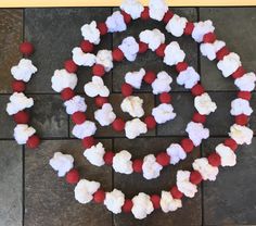 red, white and blue cotton candy beads arranged in the shape of a wreath on a brick floor