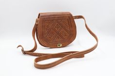 Crafted from genuine, premium-quality cow leather, our Carved Leather Bag in Camel Color is a testament to exquisite craftsmanship. This bohemian-inspired crossbody bag features a unique carved design that adds a touch of elegance and individuality. The spacious interior is divided into two compartments, providing ample space for your essentials. The beautiful camel color exudes a warm and earthy vibe, making it a versatile accessory for any occasion. Each bag is handmade and may vary slightly i Traditional Leather Saddle Bag With Adjustable Strap, Traditional Brown Satchel Saddle Bag, Traditional Brown Crossbody Satchel, Traditional Shoulder Bag With Leather Lining, Traditional Brown Leather Saddle Bag, Traditional Brown Crossbody Shoulder Bag, Bohemian Hand-tooled Saddle Bag For Travel, Traditional Leather Saddle Bag, Traditional Brown Saddle Bag For Travel