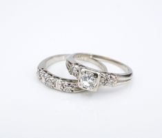 two white gold wedding rings with diamonds on each one and an engagement ring in the middle