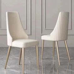 two white chairs sitting next to each other on top of a marble floor in front of a wall