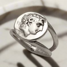 Beautifully handcrafted in sterling silver, this Alexander the Great Portrait Coin Ring is an exquisite piece of Greek jewelry. High quality and detailed, this ring features the powerful ruler's likeness, ensuring timeless style and elegance. Perfect for collectors and history enthusiasts alike. The entire ring is made of sterling silver.  Sterling Silver Ring the brightest of all precious metals Handcrafted Ring. Forget the standardized jewelry on the market! Stand out with our individually ELE Classic Sterling Silver Intaglio Ring, Timeless Silver Engraved Round Ring, Luxury Silver Sterling Silver Engraved Ring, Antique Silver Intaglio Ring, Timeless Silver Sterling Engraved Ring, Luxury Silver Rings With Intaglio, Luxury Silver Rings With Etched Details, Symbolic Engraved Sterling Silver Ring In White Gold, Symbolic Engraved White Gold Sterling Silver Ring