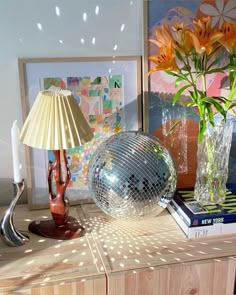 a table with a mirror ball on it next to a lamp and some flowers in vases