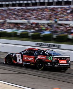 a racing car driving down a race track in front of a large crowd at an event