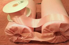 two rolls of pink ribbon with bows on them sitting on the floor next to each other