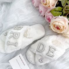 a pair of white slippers sitting on top of a fur covered floor next to flowers