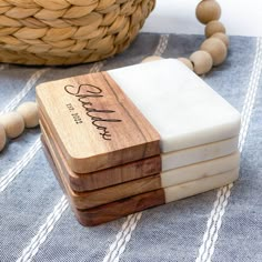 four wooden coasters sitting on top of a blue and white table cloth next to a basket