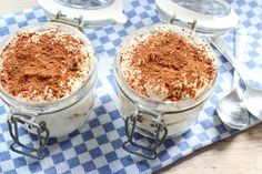 two desserts in glass containers on a blue and white checkered tablecloth with spoons