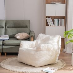 a white bean bag chair sitting on top of a wooden floor next to a green couch