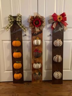 three wooden signs with pumpkins and burlocks hanging on the front door's side