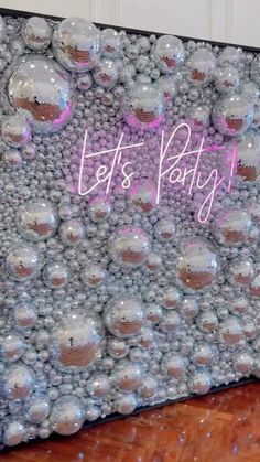 a party sign made out of balloons on top of a wooden floor with the words let's party written above it