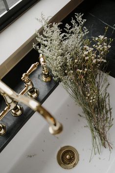 a white sink with gold faucets and flowers in it