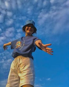 a young man standing on top of a skateboard under a blue sky with clouds