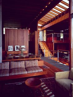 a living room filled with lots of furniture and wooden walls next to a stair case