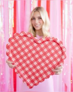 a woman is holding up a heart shaped box with gingham cloth on it