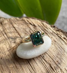 Helloooooo Maddox. She has clean lines and in 14k yellow gold, the warm tone of the metal contrasts in a fab fashion with an amazing dark rich green NEO moissanite. This ring features an emerald green 3.35 carat emerald cut NEO moissanite at the center. Available in 14k white, yellow or rose gold, also platinum. [[----- GEMSTONE DETAILS -----]] One 2.5 carat 9x7mm emerald green emerald cut ZAYA moissanite. ZAYA Moissanite by J Hollywood Designs. Includes gem cert/limited lifetime warranty. [[--- Green Moissanite Diamond Ring With Vvs Clarity, Green Diamond Ring With Vvs Clarity And Radiant Cut, Green Emerald Cut Moissanite Rings, Green Moissanite Jewelry In Radiant Cut, Emerald Cut Moissanite Rings In Bezel Setting, Green Moissanite Jewelry With Radiant Cut, Green Moissanite Radiant Cut Jewelry, Emerald Cut Moissanite Ring With Bezel Setting, Green Radiant Cut Moissanite Jewelry