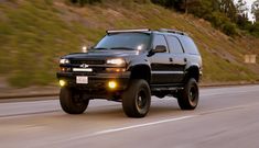 a black suv driving down the road with lights on it's front bumpers