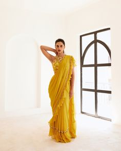 Yellow net blouse paired up with yellow predraped frill saree having hand embroidered border in between.Yellow predraped frill saree No. of pieces in a set: 3 Color: Yellow Fabric Composition: Net, georgette, opada silk Lining Material: Shantoon Closure used: Side zip in both blouse and saree Dress Length : Full Silhouette: Saree Neck type : Halter round Sleeve Length: Sleeveless Waistline: High waist Prints/ Pattterns : Plain Delivery Time: 20-25 days Traditional Ruffled Dupatta For Navratri, Anarkali Saree With Ruffles In Traditional Drape, Anarkali Pre-draped Saree With Ruffles, Ruffled Georgette Saree In Traditional Drape, Ruffled Georgette Saree With Traditional Drape, Navratri Saree With Ruffles In Traditional Drape, Traditional Yellow Ruffled Sharara, Yellow Pre-draped Saree For Wedding, Yellow Georgette Pre-draped Saree With Pallu