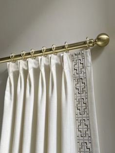 white curtains with gold metal rods hanging on the wall next to a curtain drape