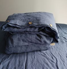 a bed with blue linens and buttons on the pillowcase is folded up to show what's inside