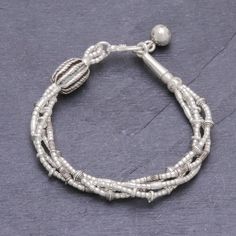 Four strands of 950 silver beads in complementary but varying patterns are twisted together to make this bracelet from Thailand's Pakaon Sojintarit. Where the ends meet a silver hook clasp is accented by a hand-stamped silver ball charm. Areas of oxidization add to the textural beauty of this piece. Karen hill tribe silver is made using techniques that have been passed down through families for generations in Thailand using only hand tools. Silver Multi-strand Spiritual Bracelets, Spiritual Silver Multi-strand Bracelets, Spiritual Multi-strand Silver Bracelets, Silver Multi-strand Bracelets With Spacer Beads, Silver Multi-strand Sterling Silver Bracelet, Silver Multi-strand Spiritual Beaded Bracelets, Silver Multi-strand Bracelets With Silver Beads, Spiritual Silver Braided Bracelet Hand-strung, Spiritual Silver Hand-strung Braided Bracelets