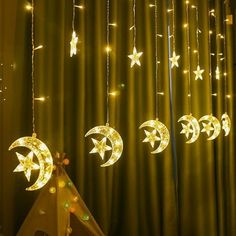 some lights that are hanging from the side of a curtain with stars and crescents on them