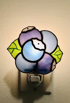 a stained glass flower is mounted on a light switch cover in a room with white walls