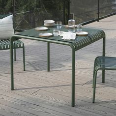 an outdoor table with two chairs and plates on it, next to a glass railing