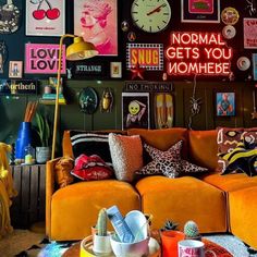 a living room filled with orange couches and lots of pictures on the wall above them