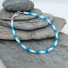 "This blue and white seed bead surf bracelet has been lovingly made using 3mm Preciosa glass seed beads. The colours take your thoughts to the sea. Threaded on strong stainless steel 7 strand Tiger Tail wire and finished with silver plated wire guardians, and a trigger clasp and optional extender chain. Matching Anklet available at: https://www.etsy.com/uk/listing/1176906774/blue-seed-bead-anklet-handmade-seed-bead?click_key=1f2ab6f3b5975f39e3558838ba932fd3e8f931cd%3A1176906774&click_sum=c0d21ed Seed Bead Anklet Patterns, Seas Bead Necklace, Anklet Seed Bead, Bracelet Ideas Sea Beads, Blue And White Seed Bead Bracelet, Seabeads Bracelets, Summer Bracelets Seed Beads, Preppy Bracelet Ideas Seed Beads, Sea Beads Bracelet