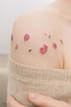 a woman's shoulder with pink flowers on the left side of her arm and chest