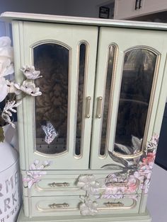 a green armoire with glass doors and flowers