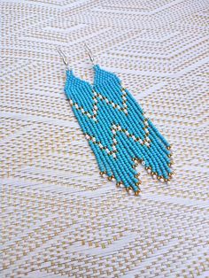 a pair of blue beads are hanging from earrings