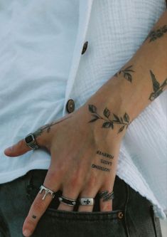 a man with tattoos on his hand and ring in his left hand, holding onto the pocket of his jeans