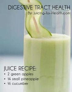 a glass filled with green juice and a cucumber in the top right corner