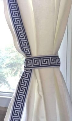 the back of a white dress with blue and black greek design on it's belt