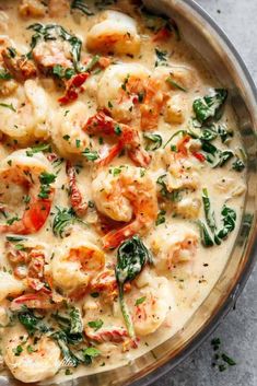 a pan filled with shrimp and spinach covered in white sauce, garnished with parsley