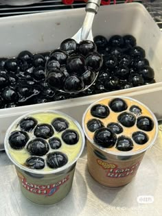 two cups of yogurt with blueberries in them next to a tray of other yogurts