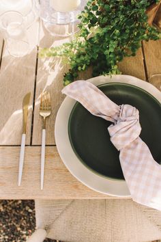 a plate with a napkin on it sitting on a wooden table next to a plant