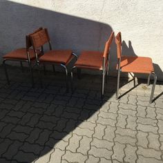 three chairs sitting next to each other in front of a white wall with a shadow on it