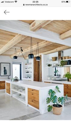 an open kitchen with white counter tops and wooden beams on the ceiling, along with potted plants