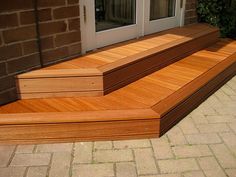 a wooden deck with steps leading up to the front door