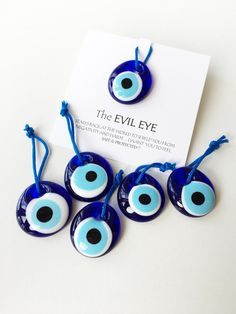 five evil eye beads with blue string and black dots on the eyes are shown in front of a white card